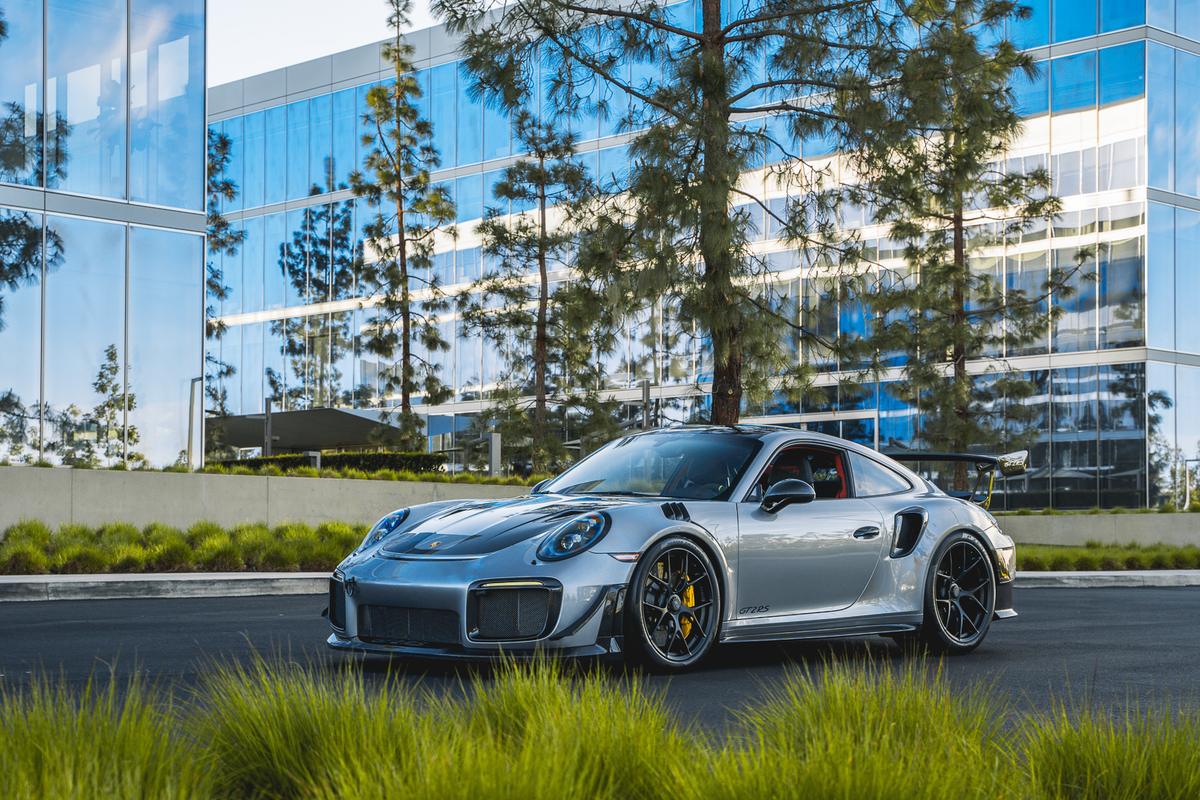 Silver Porsche 911 GT2 RS in front of a glass office building