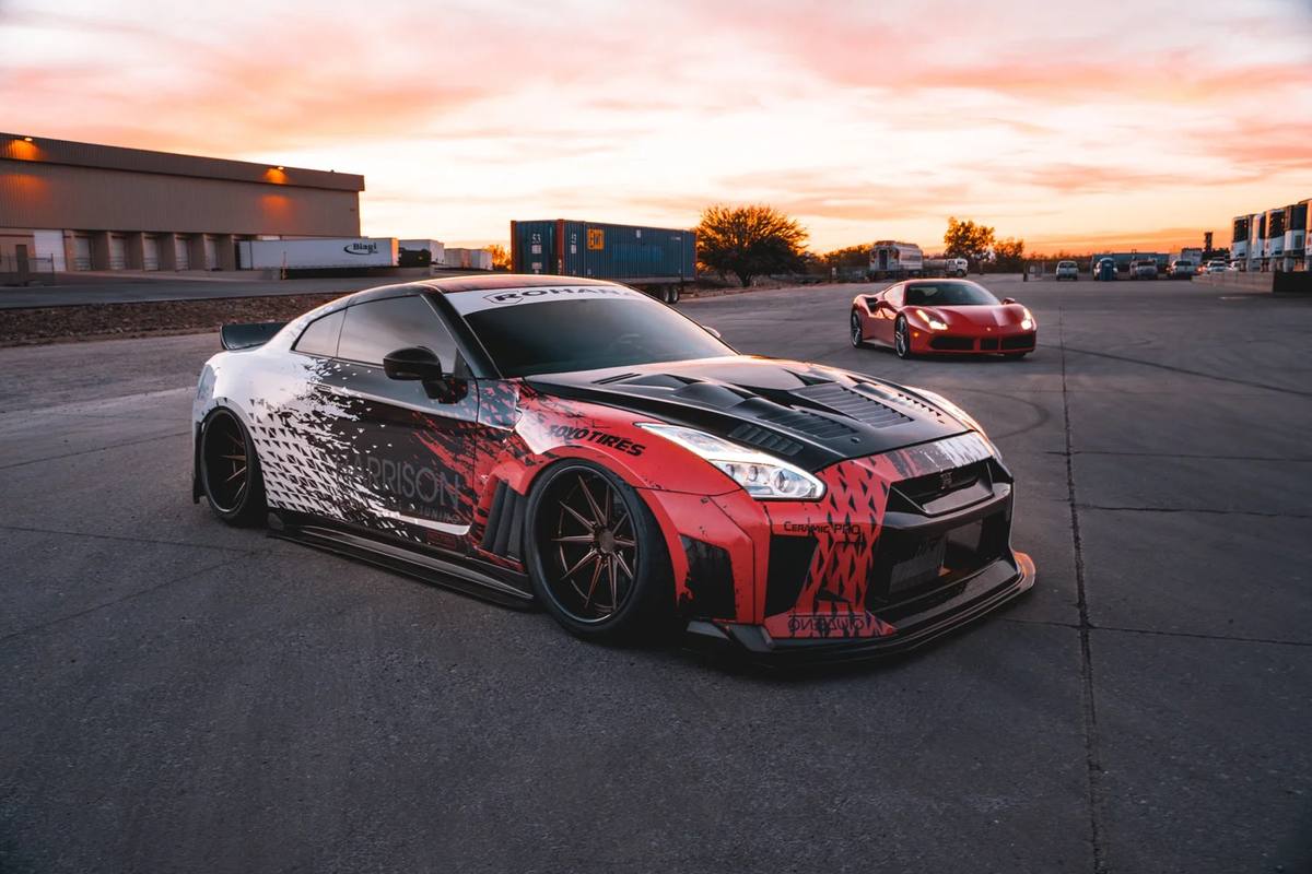 Widebody Nissan GT-R at sunset with a red Ferrari behind it