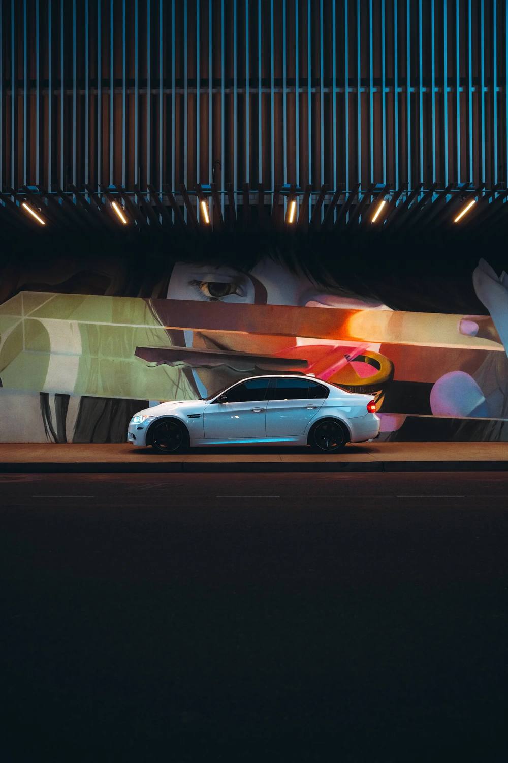 White BMW M3 in front of a neon mural