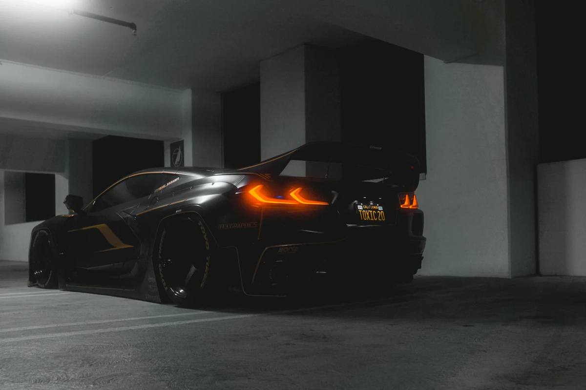 Black sports car with glowing taillights in a parking garage