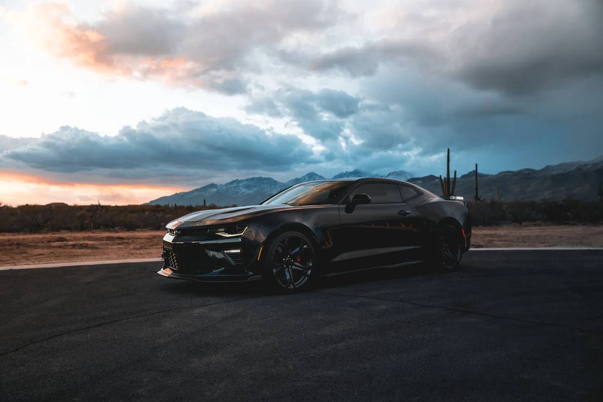 Black coupe under a dramatic desert sky