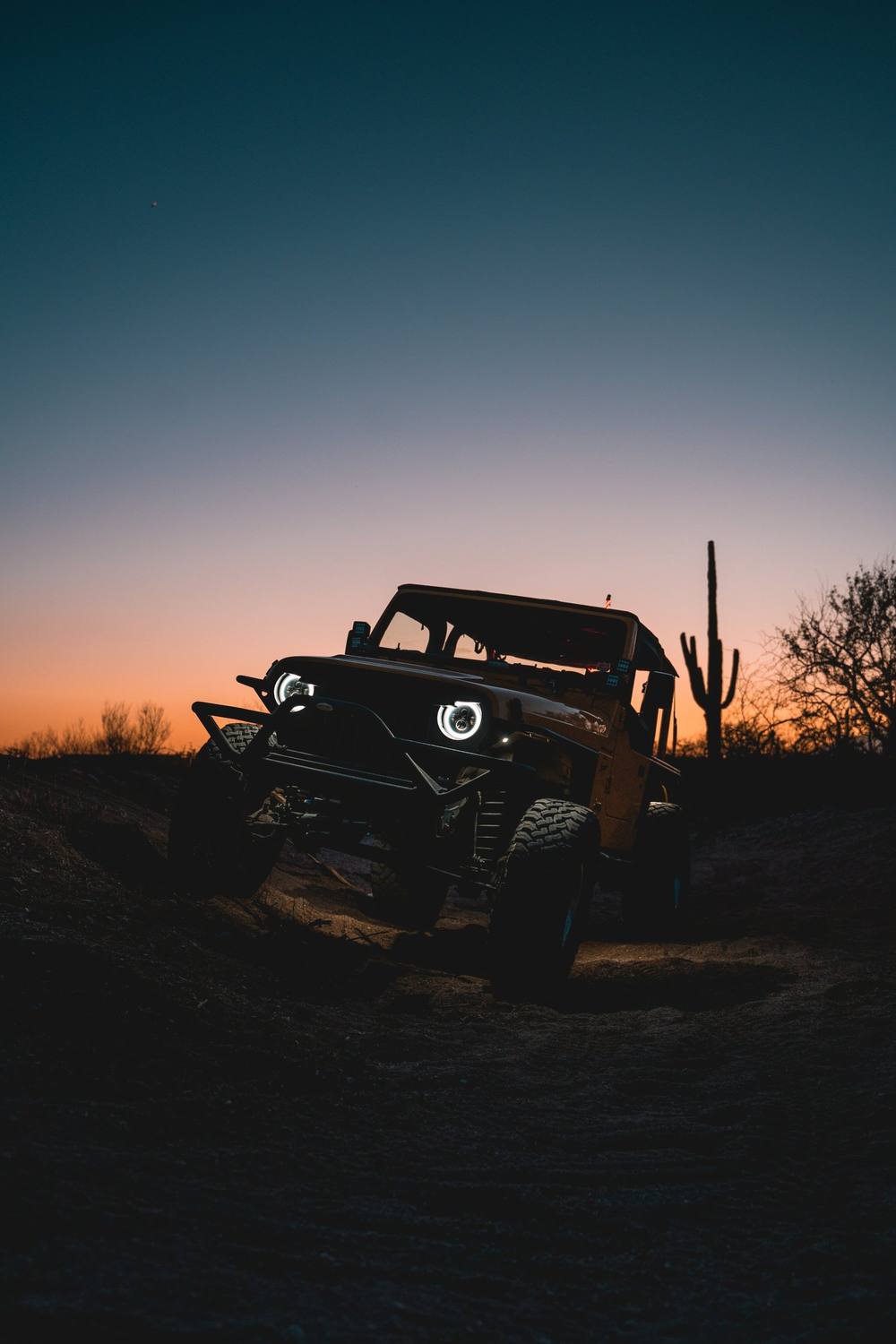Jeep silhouetted against a desert sunset
