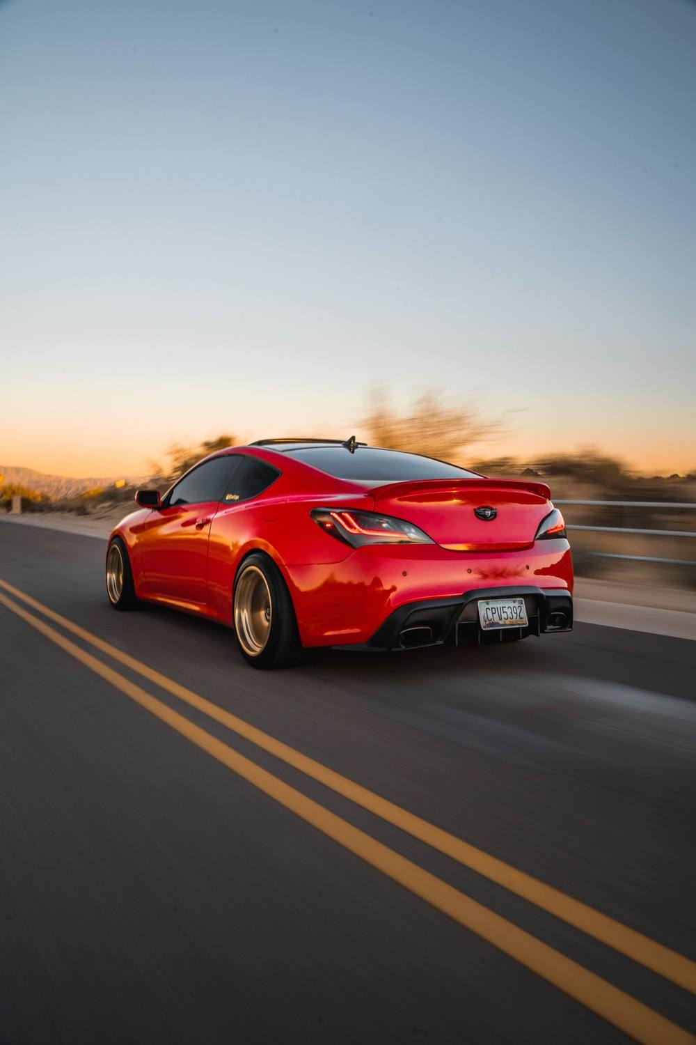 Red coupe rolling shot on a desert road