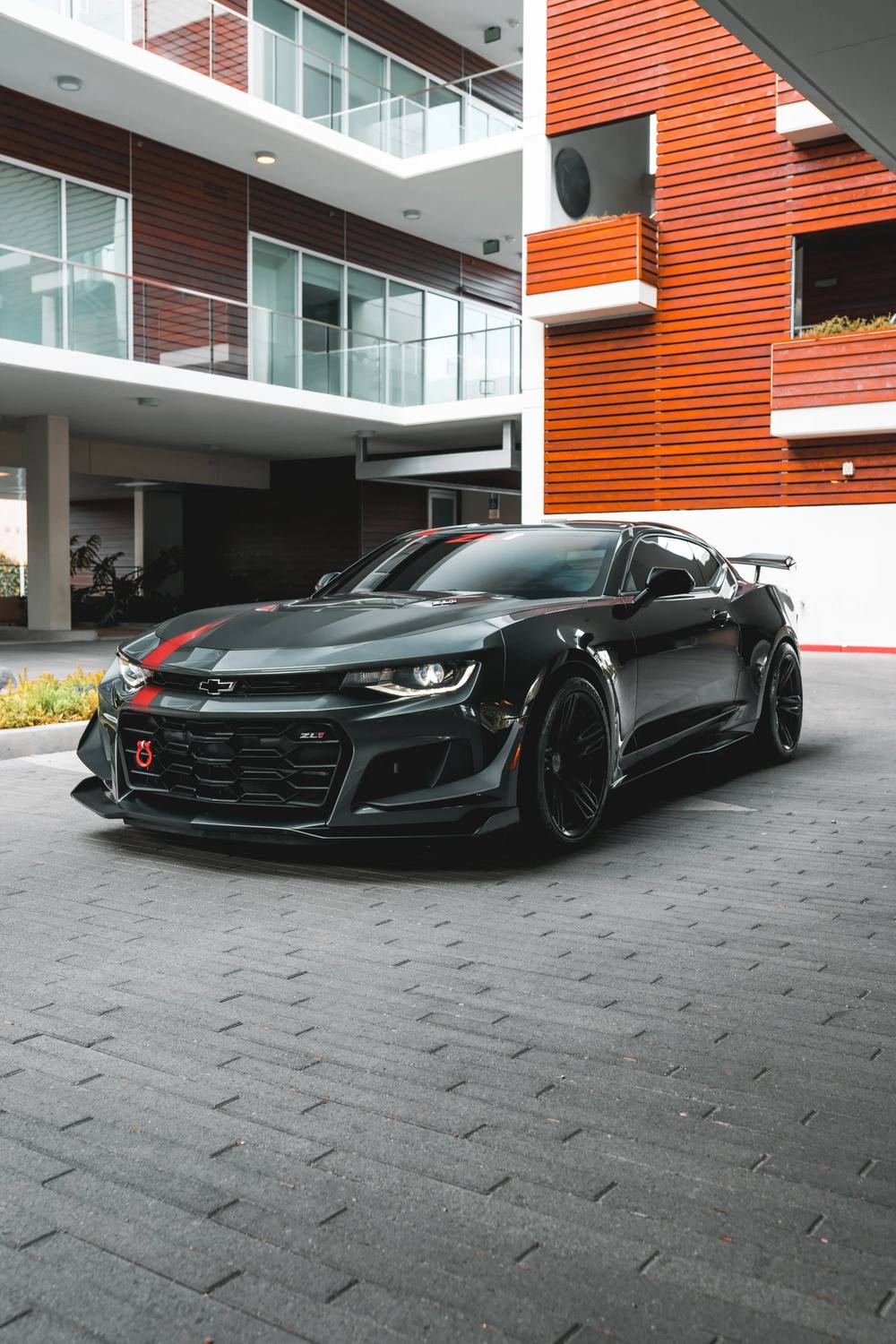 Black Camaro ZL1 outside a modern apartment building